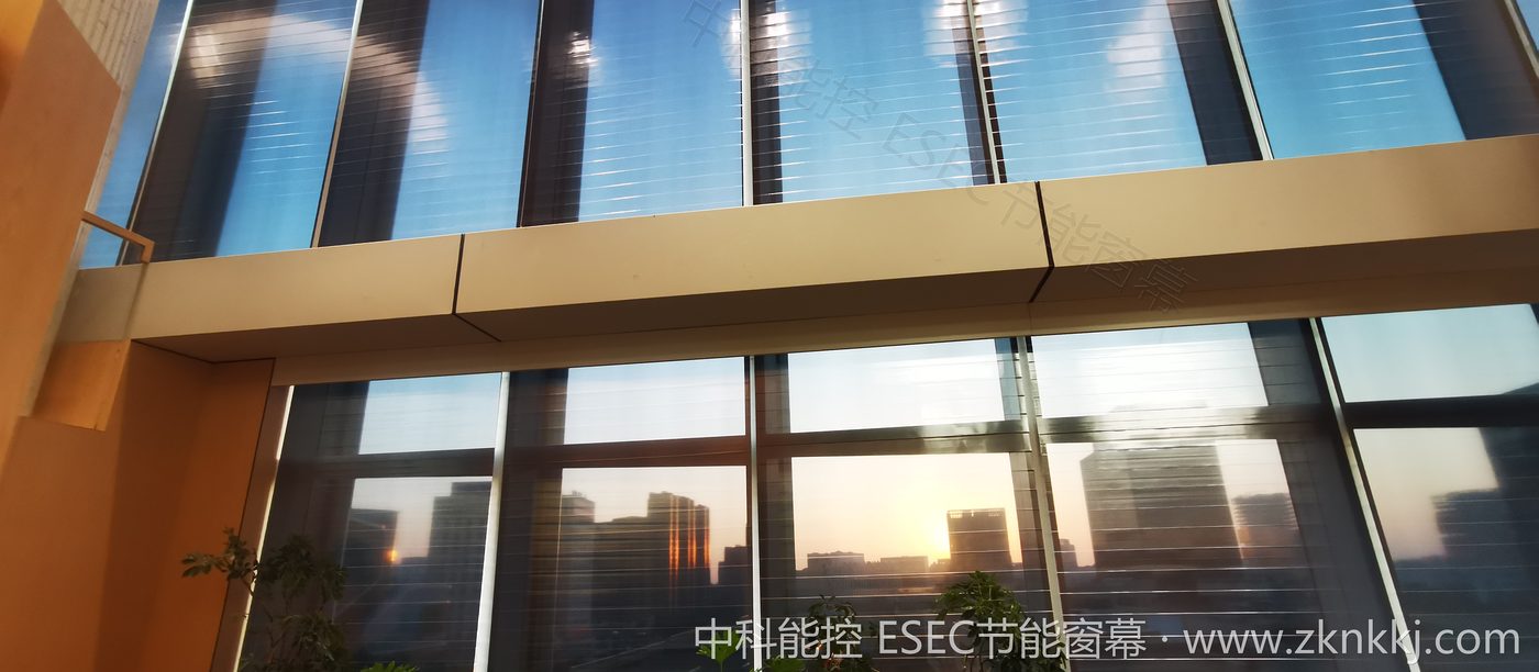 Double-height lobby · full-wall curtain at sunset
