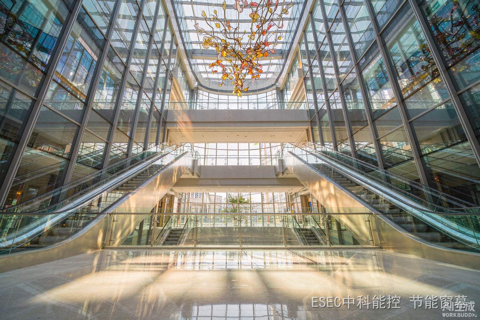 商场中庭挑空玻璃幕墙与采光顶,午后阳光洒进中庭