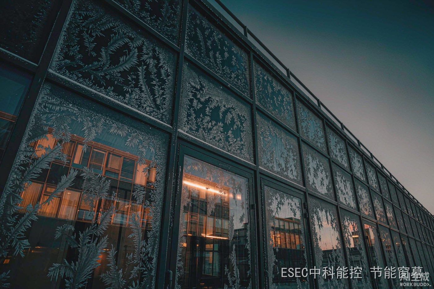 晴朗冬夜的玻璃幕墙外表面结满霜花,室内透出暖光