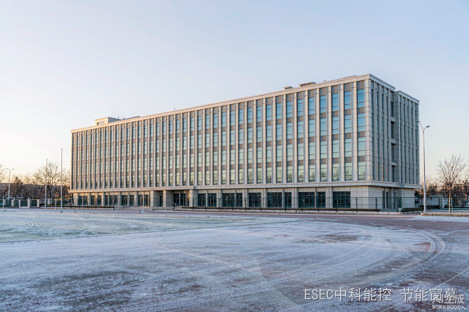 冬日清晨的教学楼玻璃幕墙外景,操场覆着薄霜